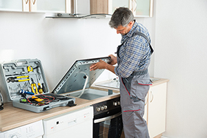Photo Of mature repairman examining stove in kitchen